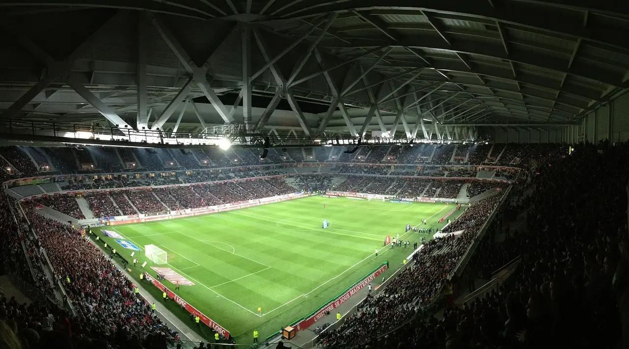 Oplyst fodboldstadion med bane og tilskuere